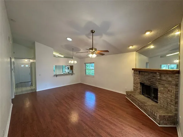 an empty room with wooden floor fireplace and ceiling fan
