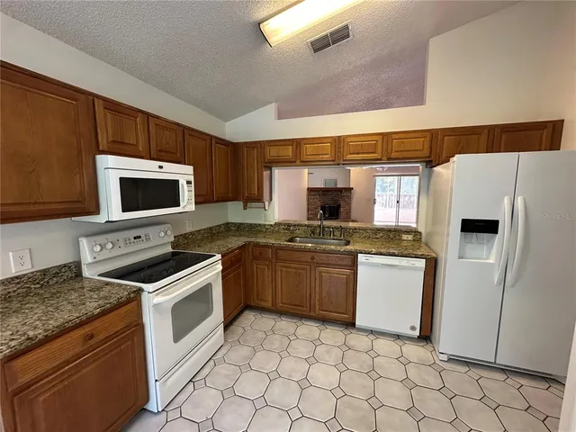 a kitchen with stainless steel appliances granite countertop a stove top oven microwave and a refrigerator