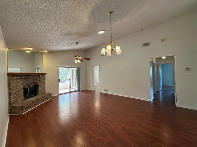 a view of an empty room with wooden floor fireplace and a window