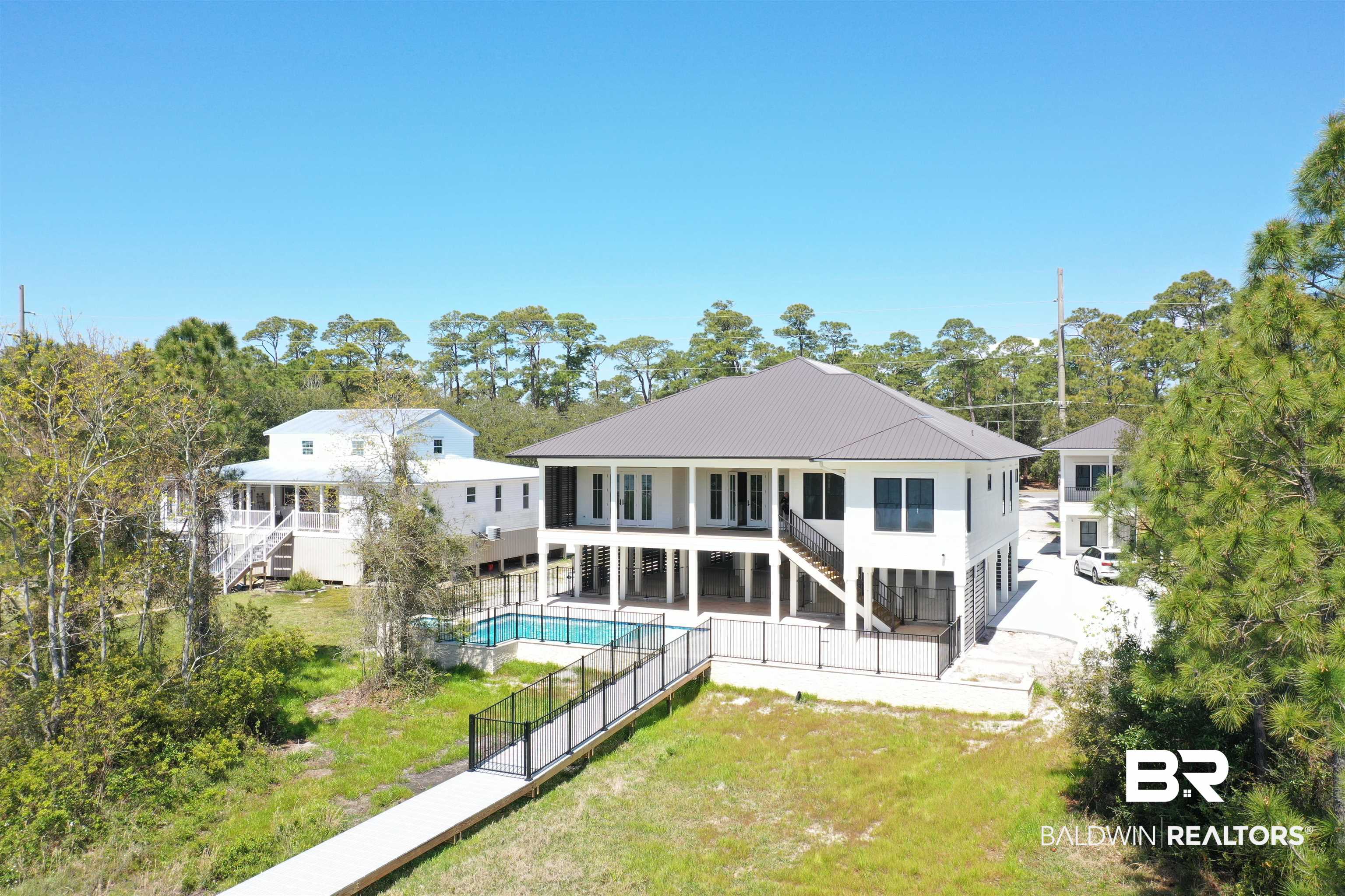 14686 State Highway Gulf Shores, AL 36542 - Photo 42 of 44 Rear view of house with a yard, a patio, a fenced in pool, and stairs