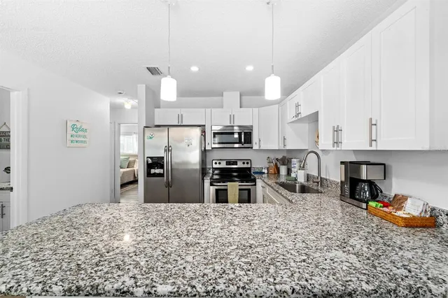 a kitchen with stainless steel appliances kitchen island granite countertop a stove refrigerator and cabinets