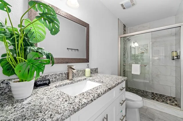 a bathroom with a granite countertop sink a toilet and shower