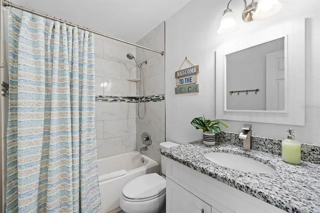 a bathroom with a granite countertop sink a toilet and shower
