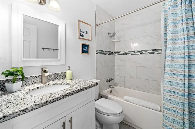 a bathroom with a granite countertop sink a toilet and shower
