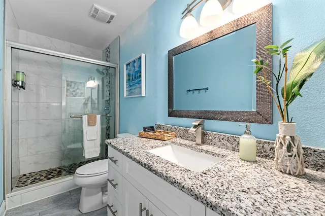 a bathroom with a granite countertop sink a toilet and shower