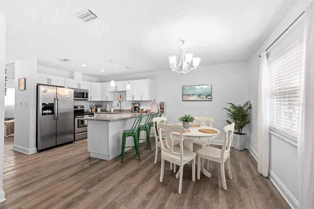 a view of a dining room with furniture a kitchen and chandelier