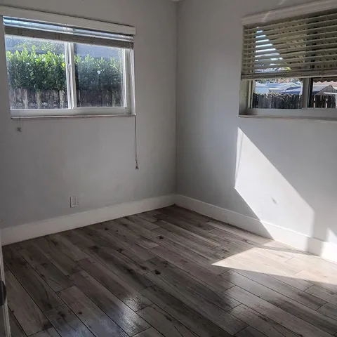 a view of empty room with window and wooden floor