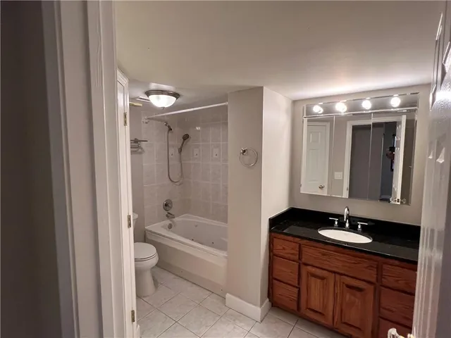 a bathroom with a granite countertop sink a toilet a mirror and shower