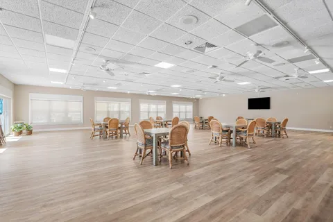 a large room with wooden floor pool table and windows