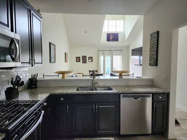 a kitchen with stainless steel appliances granite countertop a sink stove and cabinets