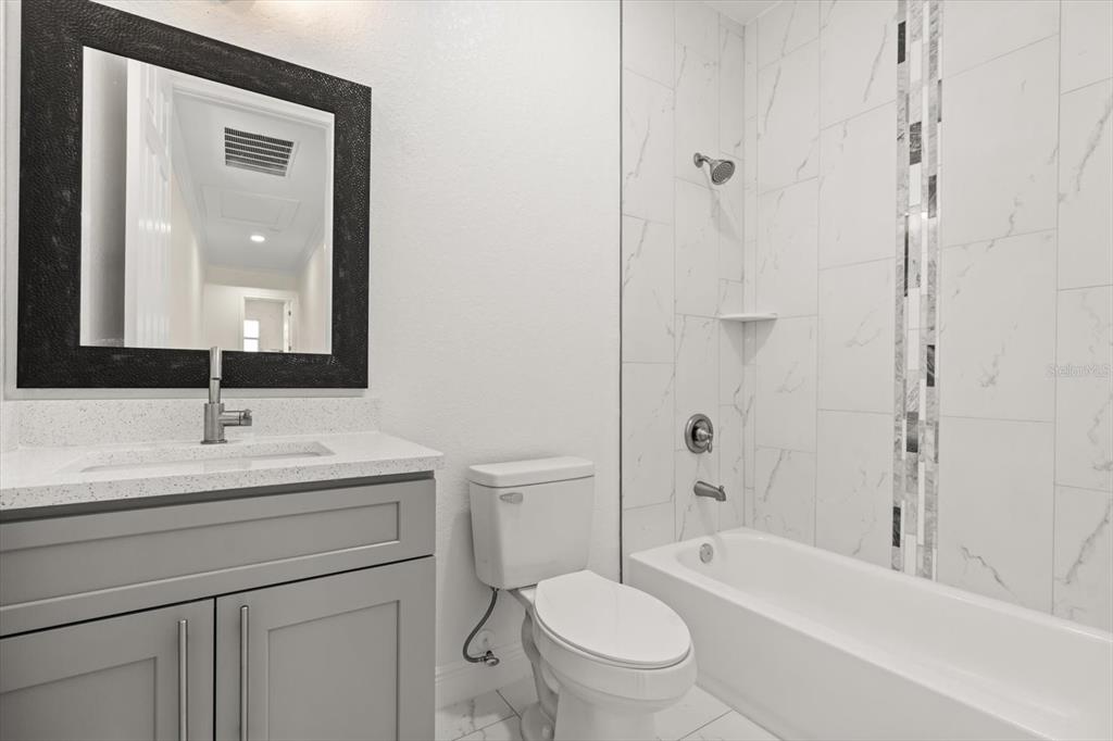 840 Oaks Shores Road Leesburg, FL 34748 - Photo 15 of 25 a bathroom with a toilet a sink a mirror a bathtub and shower