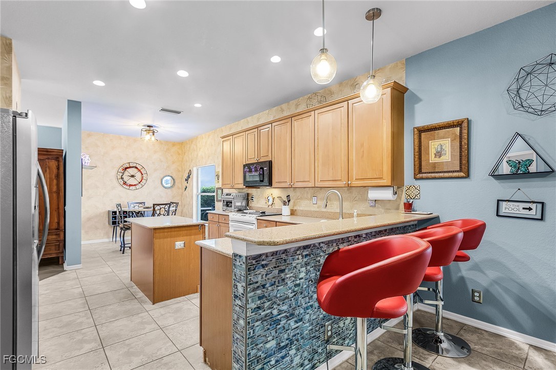 9021 Falcon Pointe Loop Fort Myers, FL 33912 - Photo 11 of 39 a kitchen with stainless steel appliances granite countertop a table chairs sink refrigerator and microwave