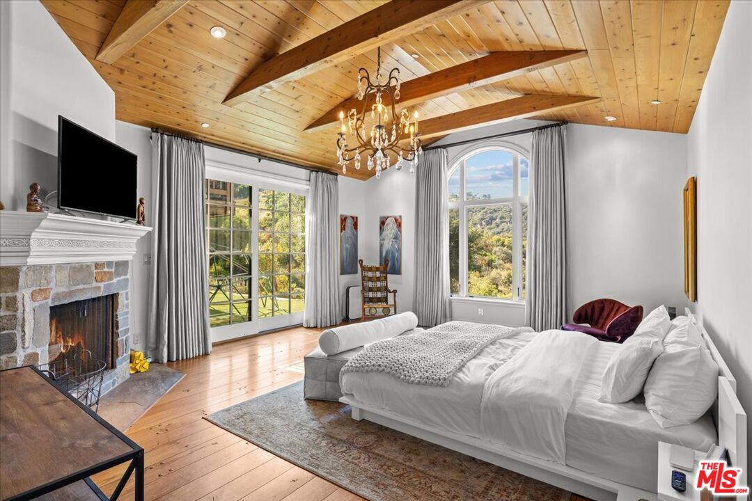 2373 Tuna Canyon Road Topanga, CA 90290 - Photo 21 of 54 a bedroom with a bed a flat screen tv and a fireplace