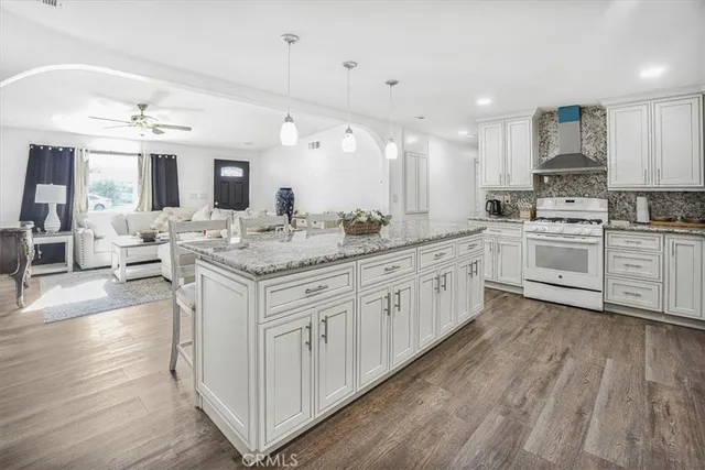 a large kitchen with stainless steel appliances kitchen island granite countertop white cabinets and window