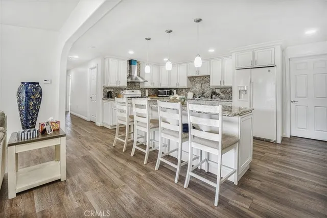 a kitchen with stainless steel appliances kitchen island granite countertop a wooden floor and white cabinets
