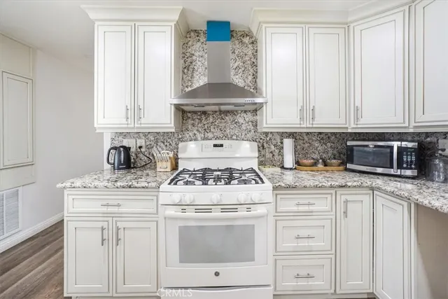 a kitchen with kitchen island granite countertop lots of white cabinets stainless steel appliances and a center island
