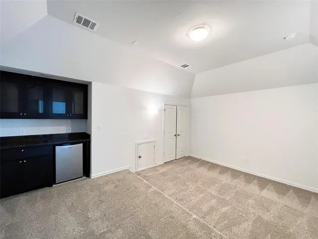 a view of an empty room with a kitchen and a window