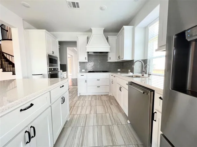 a kitchen with granite countertop a sink stove refrigerator and cabinets