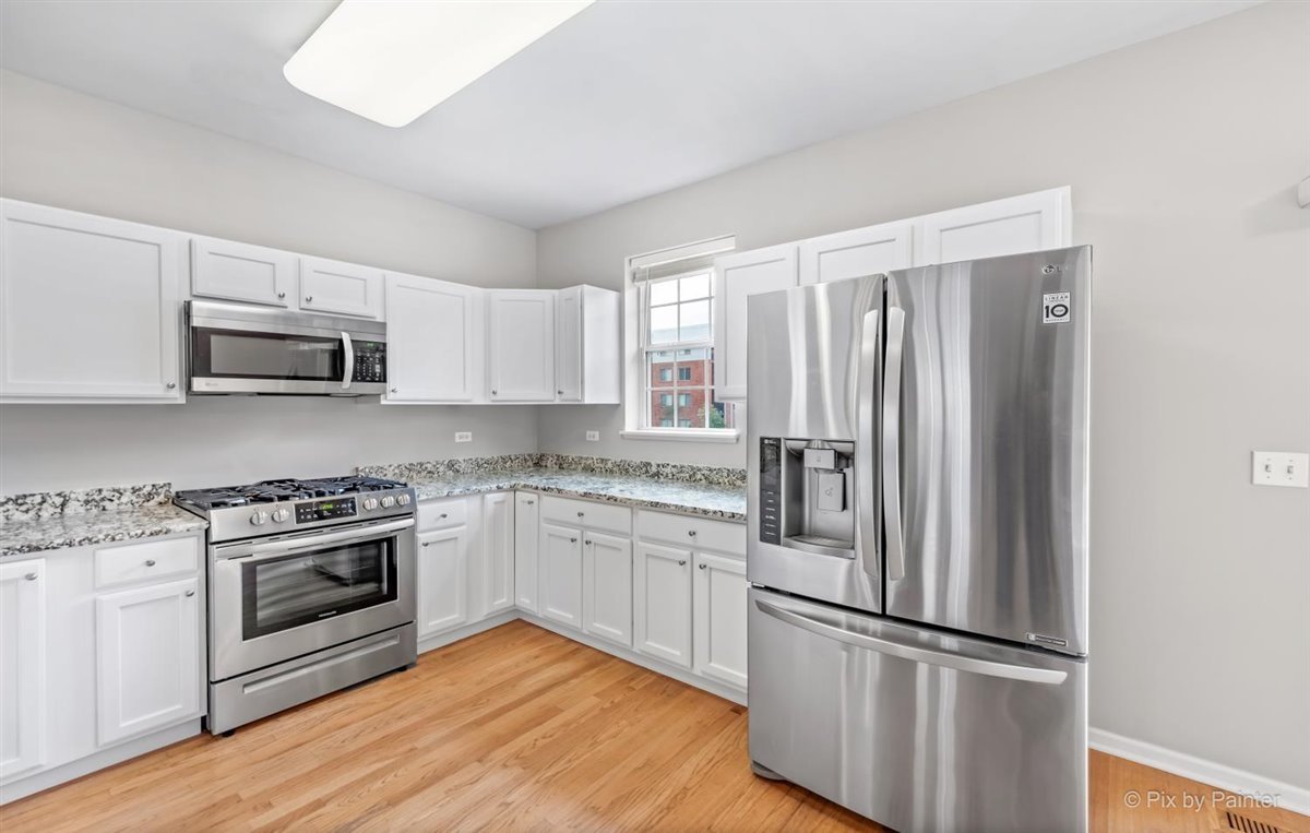 172 East River Road, Unit L Des Plaines, IL 60016 - Photo 11 of 27 a kitchen with cabinets stainless steel appliances and wooden floor