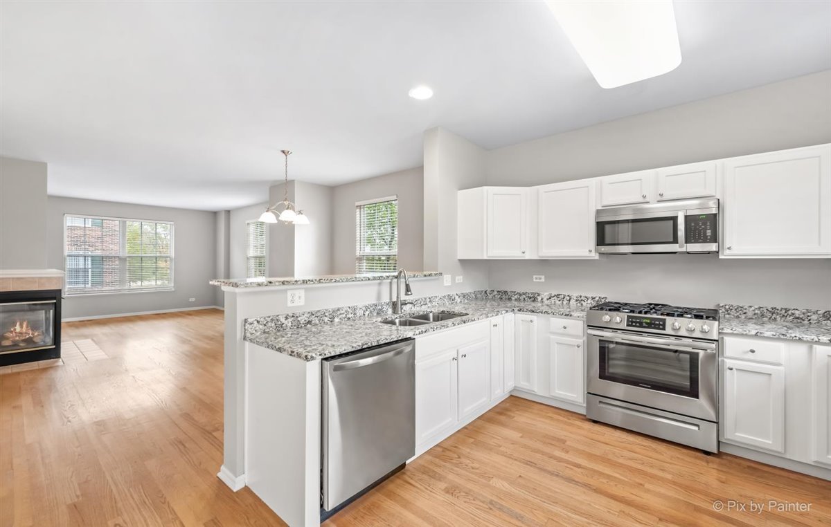 172 East River Road, Unit L Des Plaines, IL 60016 - Photo 12 of 27 a kitchen with stainless steel appliances granite countertop a stove top oven a sink dishwasher and a microwave oven with wooden floor
