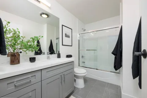 a bathroom with a granite countertop sink a toilet a mirror and shower