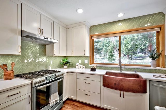 a kitchen with stainless steel appliances white cabinets stove and sink