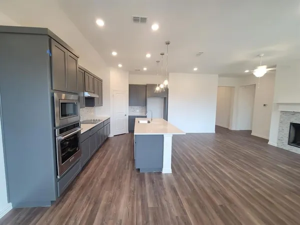 a large kitchen with kitchen island a stove a sink dishwasher and a oven with cabinets