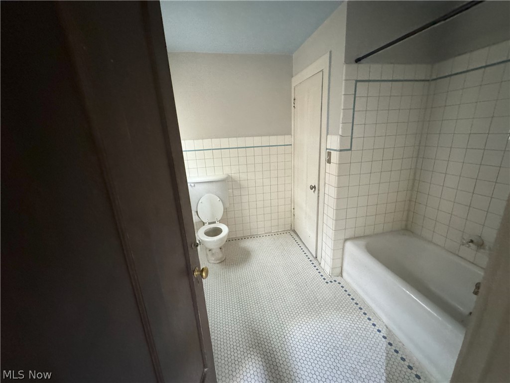 317 Center Road Bedford, OH 44146 - Photo 16 of 16 Bathroom featuring toilet, tile walls, tiled shower / bath combo, and tile floors