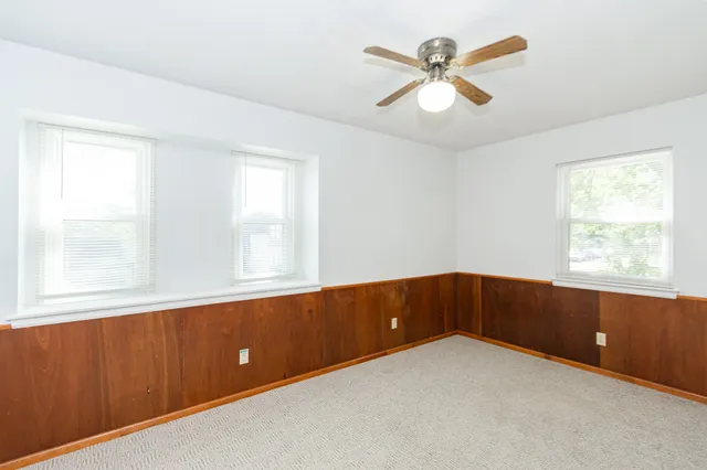 an empty room with windows and ceiling fan