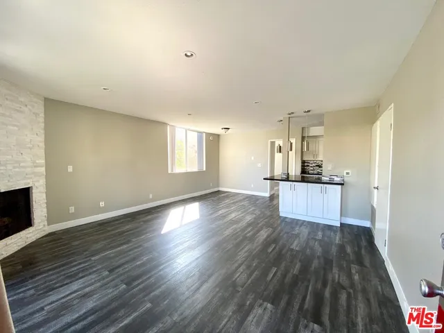 a view of kitchen and empty room with wooden floor