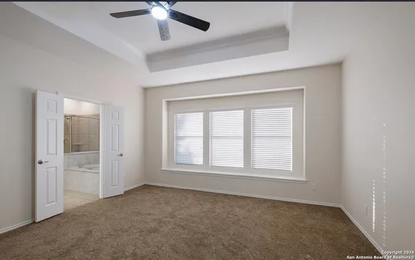 an empty room with chandelier fan and windows