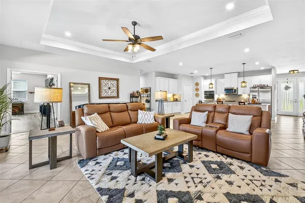 a living room with furniture kitchen view and a chandelier