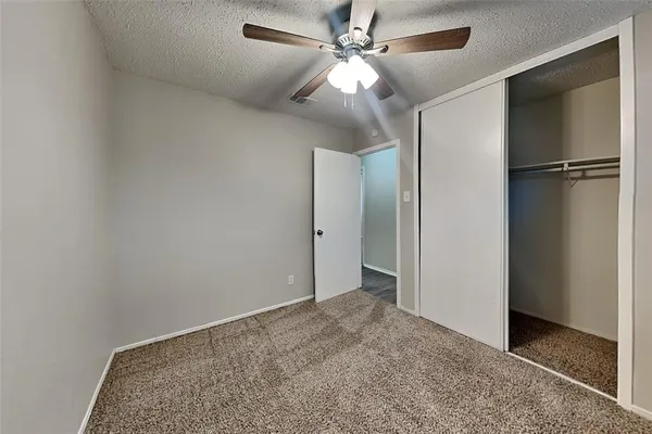 an empty room with closet and a ceiling fan
