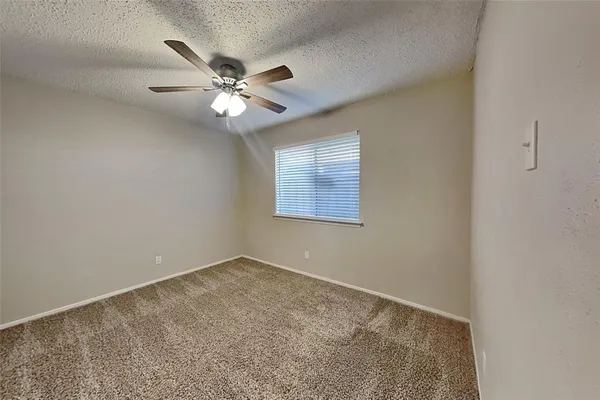 an empty room with a window and a ceiling fan