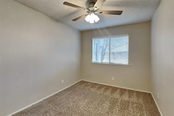 an empty room with a window and a fan