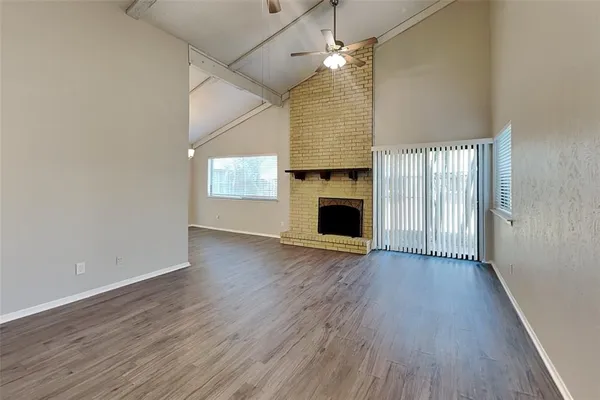 an empty room with wooden floor fireplace and windows