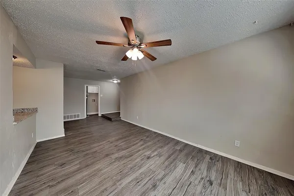 a view of a room with wooden floor and a ceiling fan