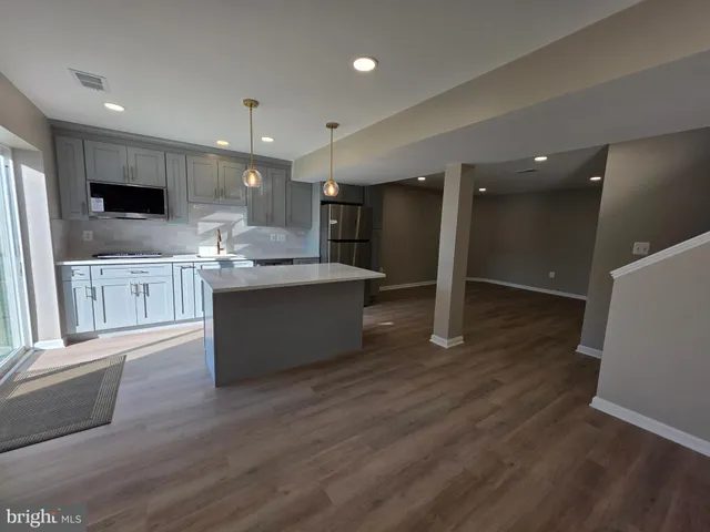 a large kitchen with stainless steel appliances kitchen island a large counter top and a wooden floors