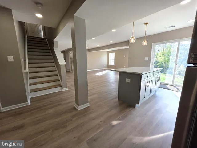 a kitchen with stainless steel appliances granite countertop a refrigerator a sink and wooden floors