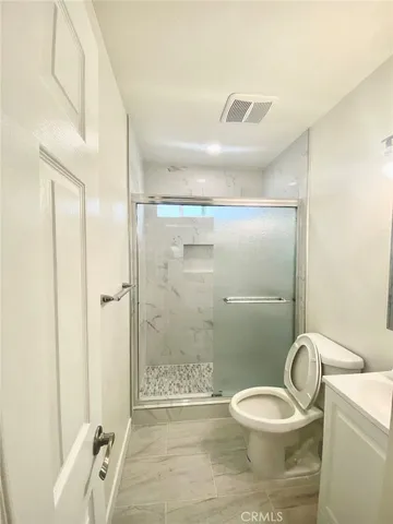 a bathroom with a granite countertop toilet a sink and a mirror