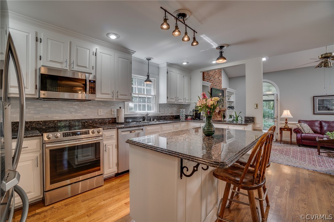 13131 Drakewood Road Midlothian, VA 23113 - Photo 12 of 29 a kitchen with stainless steel appliances granite countertop a stove top oven a sink dishwasher a dining table and chairs with wooden floor