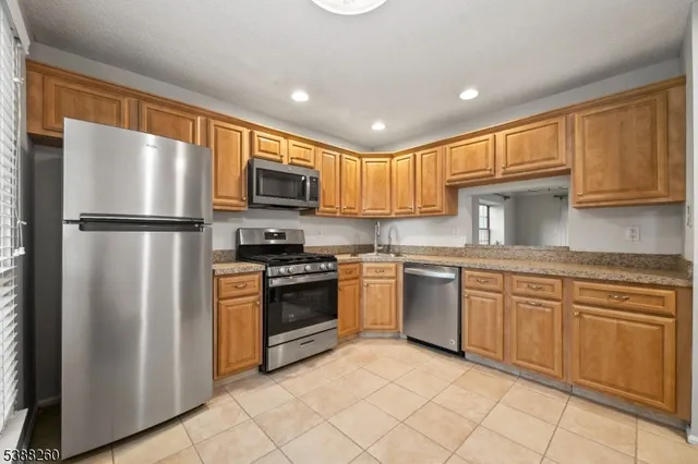 a kitchen with granite countertop cabinets stainless steel appliances and a window