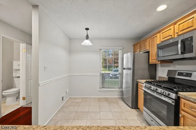 a kitchen with stainless steel appliances granite countertop a refrigerator a stove and a sink with granite countertops