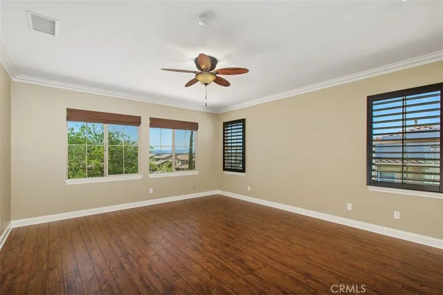 a view of an empty room with a window and wooden floor