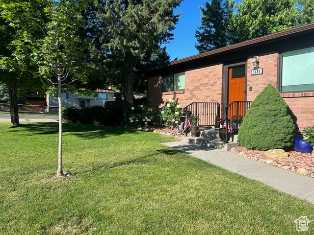 Exterior space with fence, a front lawn, and brick siding