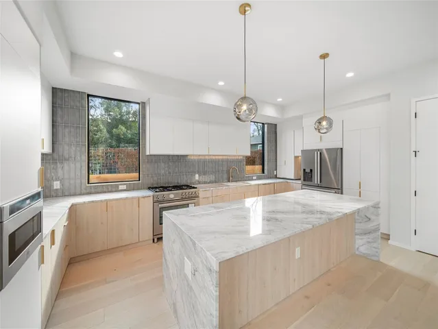 a large kitchen with kitchen island a large counter top and stainless steel appliances