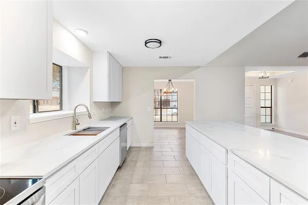 a large white kitchen with a sink and dishwasher a stove with wooden floors