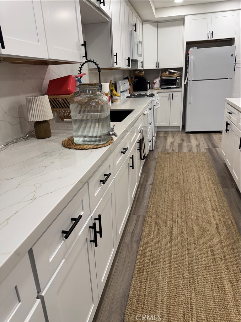682 East Workman Street Covina, CA 91723 - Photo 9 of 34 a kitchen with kitchen island granite countertop wooden floors and white cabinets
