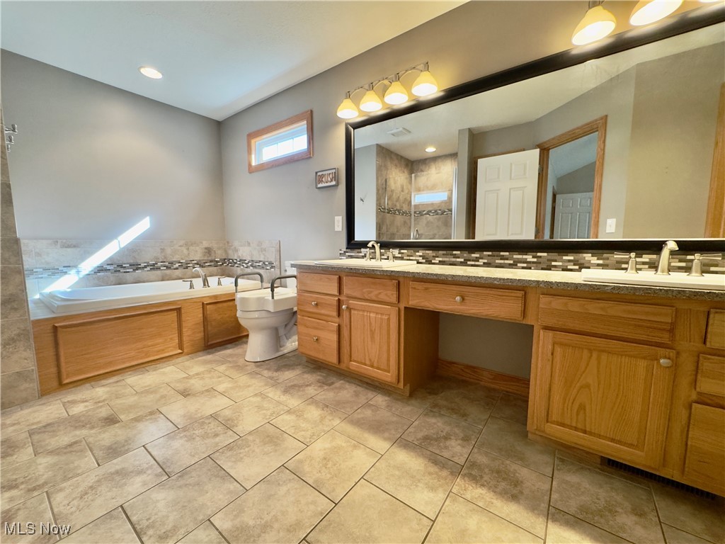 6014 Wentworth Road Southwest Canton, OH 44706 - Photo 11 of 22 Primary bathroom featuring tasteful backsplash, double vanity, a garden tub, and recessed lighting