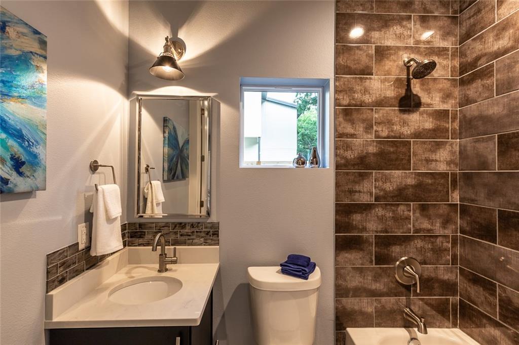 1142 Eleanor Street, Unit 2 Austin, TX 78721 - Photo 21 of 24 An inviting bathroom offers a modern vanity, sleek mirror, and a tiled shower-tub combination.